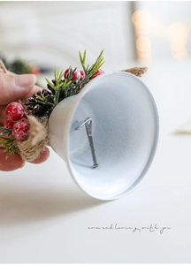 Close-up of white metal Christmas bell with red berries, pine cones and a jute rope