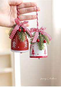 Detail of red and white iron Christmas bells with pine needles, berries and plaid bows
