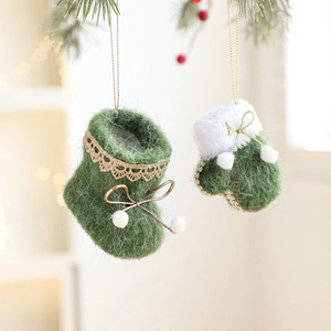 Christmas green wool felt glove and boot ornaments hanging on a pine tree branch