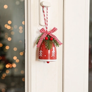 Red Christmas bell ornament with plaid bow, pine needles and berries on white door