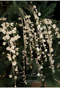 Close-up of white crystal petals and gold twigs on a Christmas tree with warm lights