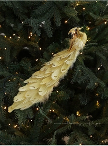 Dettaglio di un pavone dorato con piume e paillettes su un albero di Natale