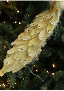 Dettaglio decorazione natalizia in piume bianco crema con glitter oro su un albero