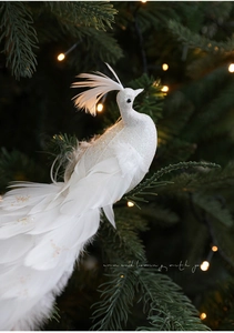 Dettaglio pavone di Natale bianco con glitter e piume su un ramo di albero