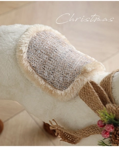 Detailed texture of white plush Christmas reindeer with knit saddle and pine needle accents