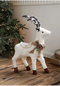 Detail of white plush reindeer with burlap bow, pine cones and festive ornaments