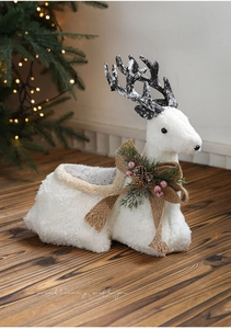 Detail of white plush reindeer decor with burlap bow, pine cones and red berries accents