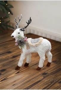 Close-up of white plush Christmas reindeer ornament with pine cones and knitted saddle details