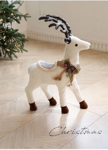 Detail of a white plush Christmas reindeer with burlap bow and red berry accents