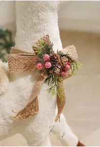 Close-up of white plush Christmas reindeer with pine cones, berries and burlap bow decoration