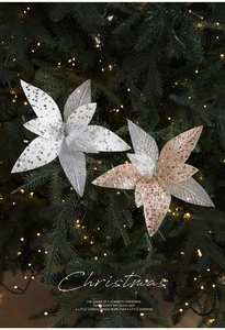 Detailed view of champagne and silver sequined Christmas flowers on a lit tree