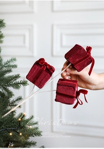 Close-up of burgundy velvet Christmas gift boxes on white frosted twigs for tree decor