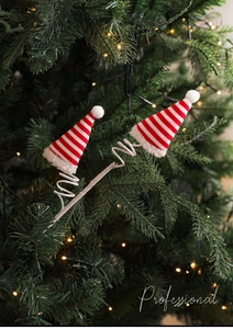 Detailopname van rood gestreepte kerstmutsen met pluche ballen op een kerstboomtak