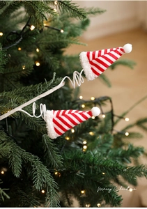 Detail van rood-wit gestreepte mini pluche mutsen met spiraaldraad op de kerstboom