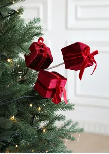 Close-up of red velvet gift box picks with silk bows on a glowing Christmas tree