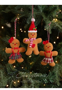 Close-up of three gingerbread man plush ornaments hanging on a glowing Christmas tree