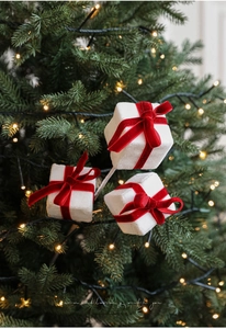 Christmas tree pick featuring white velvet gift boxes with red bows in a festive setting