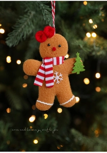 Detail of felt gingerbread man ornament with red scarf and green tree on a festive background