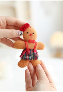 Close-up of cute gingerbread girl plush ornament with red bow and plaid skirt detail