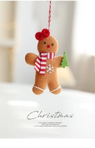 Detail of gingerbread man plush ornament with red bow, scarf, and green tree