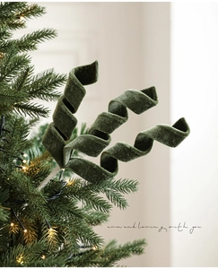 Dettaglio di rami a spirale in velluto verde scuro inseriti in un albero di Natale illuminato