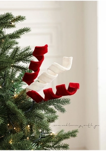 Dettaglio di spirali in velluto rosso e bianco su un albero di Natale con luci calde