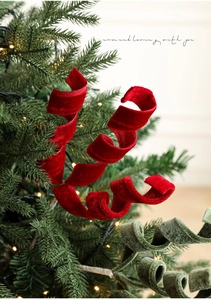 Dettaglio di nastri a spirale in velluto rosso e verde su un albero di Natale con luci