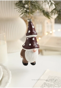 Close-up of a festive Christmas gnome ornament hanging on an evergreen tree branch