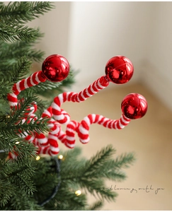 Detail of plush Christmas spray with red metallic spheres and spiral candy cane stems
