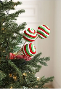 Close-up of red and green candy cane picks with plaid bows on a festive Christmas tree