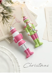 Detail of pink and green painted nutcracker ornaments with gold strings on pine branches