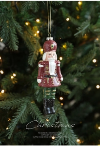 Macro shot of painted nutcracker soldier ornament hanging on a warm lit Christmas tree