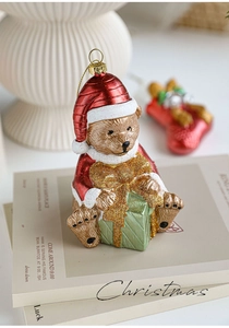 Detail of Christmas teddy bear ornament holding green gift box on stacked books