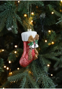 Detail of red Christmas stocking ornament with glitter bow and bells on a lit tree
