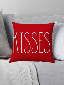 Detail of red plush pillow case with white Kisses text on a modern grey sofa