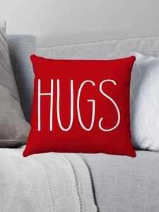 Detail of red plush pillow case with white HUGS text on a modern grey sofa