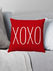 Detail of red plush pillow case featuring white XOXO text on a modern grey sofa