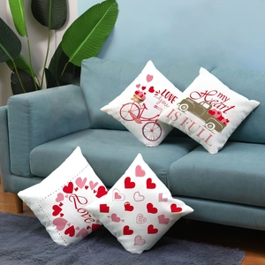 Detail of four Valentine's pillow covers with bicycle and heart prints on a blue sofa