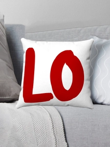 Détail d'une housse de coussin en peluche blanche avec lettres rouges sur un canapé