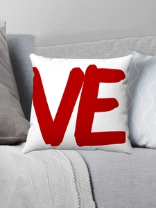 Détail de la taie d'oreiller en peluche avec motif Love rouge sur canapé gris