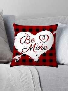 Detail of red buffalo plaid pillow with white heart and Be Mine text on a sofa