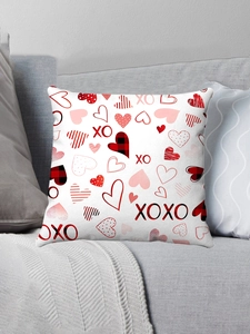 Detail of white plush pillow cover with red heart patterns and XOXO print on gray sofa