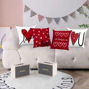 Détail de quatre coussins en peluche rouge et blanc avec motif cœur sur un canapé