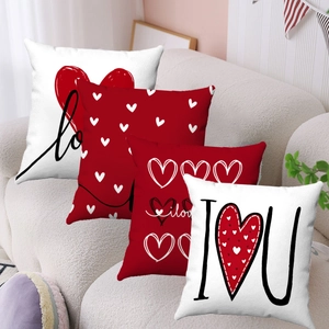 Détail des taies d'oreiller en peluche rouge et blanc avec motifs de cœur et Love sur canapé