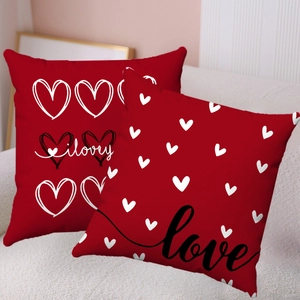 Détail de deux housses de coussin en peluche rouge avec motif cœur et texte Love