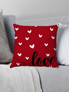 Gros plan d'un coussin en peluche rouge avec motifs cœurs et texte Love noir