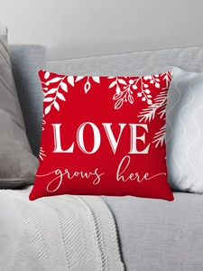 Detail of red plush pillow case with white Love Grows Here print on gray sofa