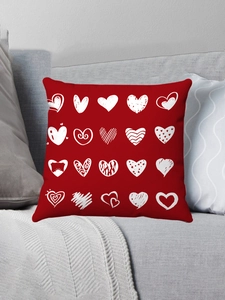Detail shot of red plush pillow case with white heart patterns on a gray sofa