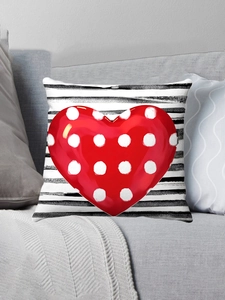 Detail of red polka dot heart on striped plush pillow cover on a gray sofa