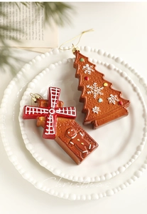 Detail of gingerbread man and Christmas tree resin pendants on a decorative white porcelain plate